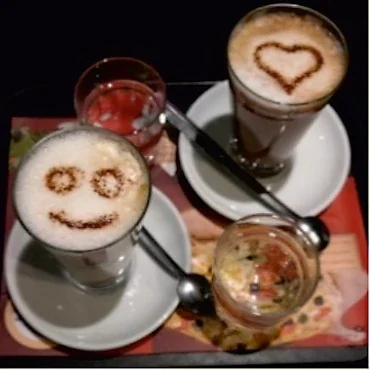 Zwei Tassen Cappuccino mit einem Herz und einem Smiley