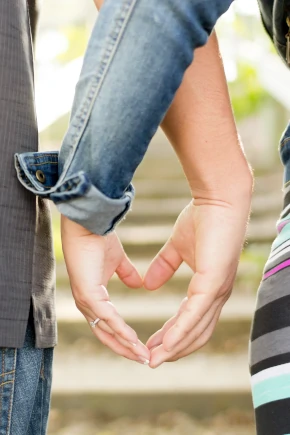 Mann und Frau mit überkreuzten Armen formen mit den Händen ein Herz - "Mut zur Liebe"