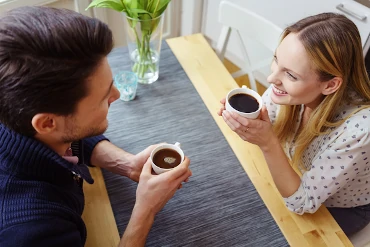 Ein Mann und eine Frau sitzen mit einer Tasse Kaffee am Tisch