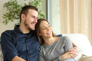Kurse für Paare: Paar sitz glücklich auf dem Sofa Arm in Arm