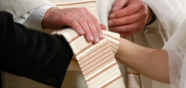 Die Stola des Priesters liegt um die ineinander gelegten Hände des Brautpaares