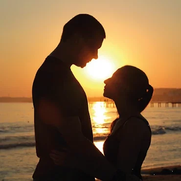 Romantischer Sonnenuntergang am Meer mit einem verliebten Paar als Mann und Frau